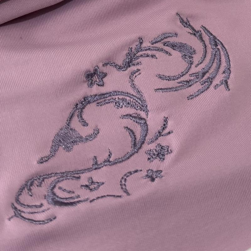 The same swirl design stitched in lavender thread on a pink knit garment